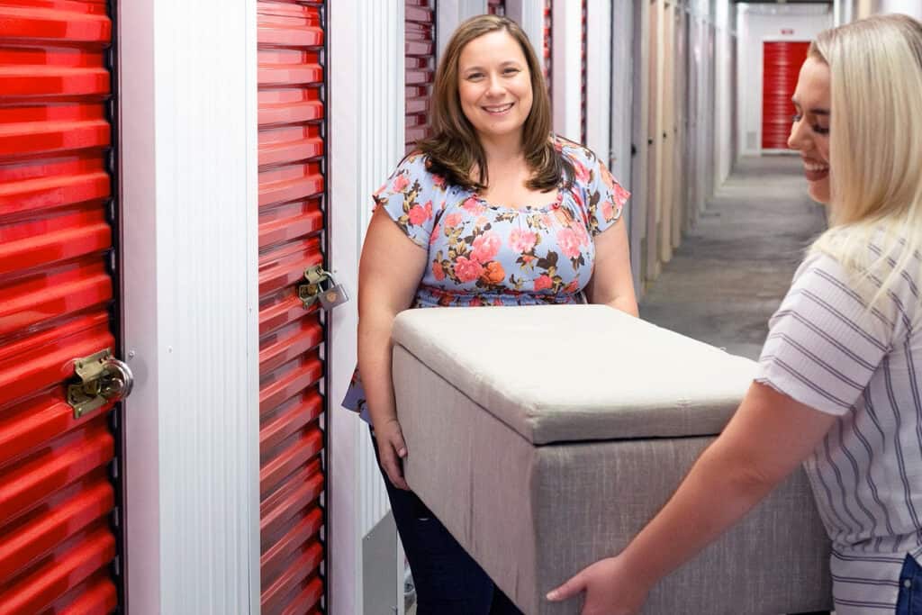 Women moving couch into storage unit