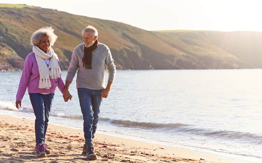 downsizing tips for seniors. two seniors walking on a beach