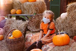 child at pumpkin patch in face mask