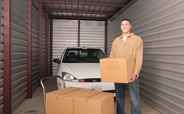 young man stores car and boxes in storage unit